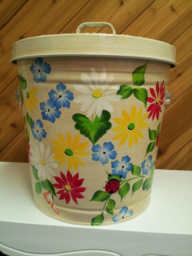 A light yellow can with white, yellow, and blue flowers with a pink butterfly and a ladybug