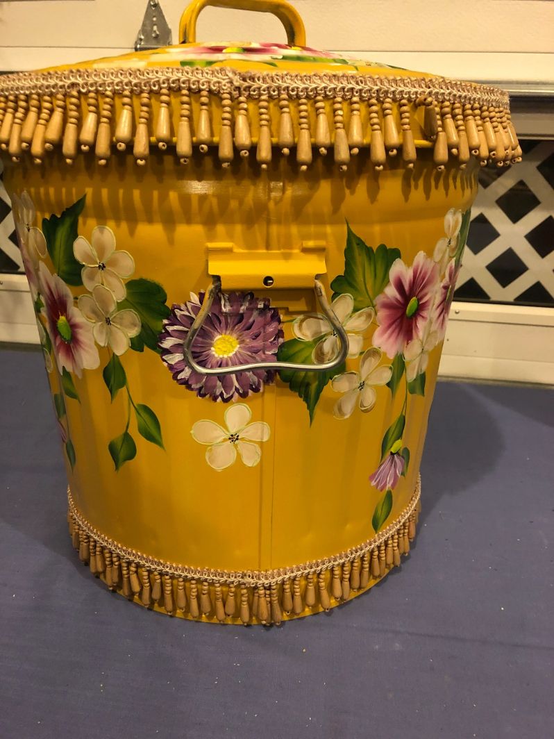 A yellow can with pink, purple, and white flowers