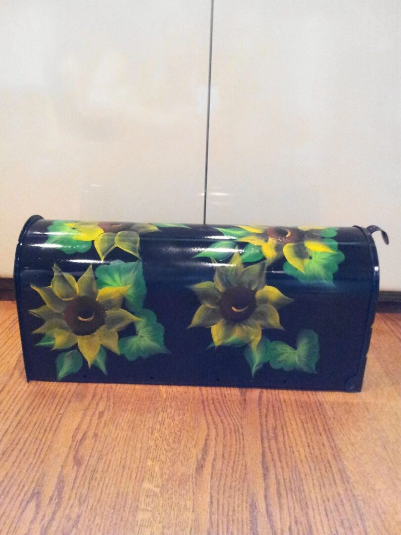 Mailbox black with bright yellow sunflowers, greenery. The Painted Can