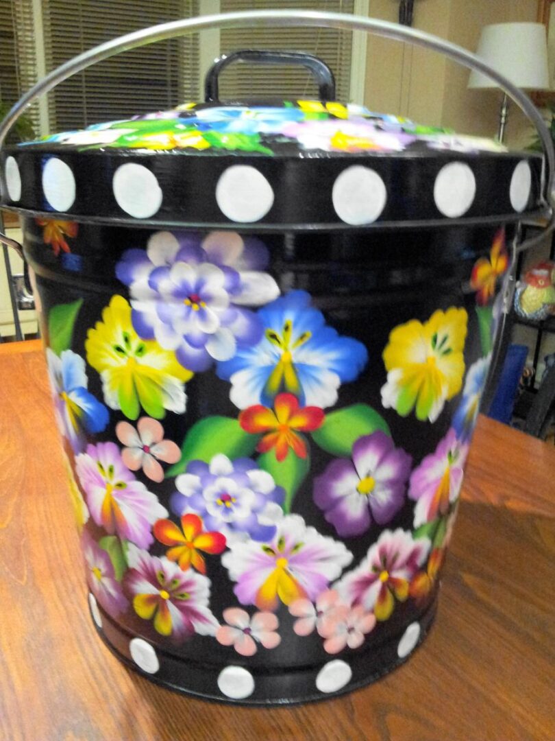 A black can with huge white polka dots and colorful flowers