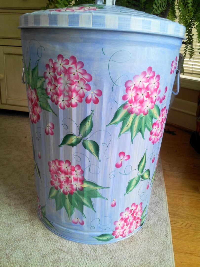 A can with light blue and white pattern and bunches of pink flowers