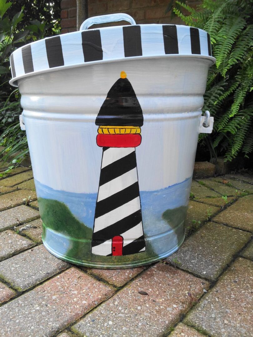 A can with a black, white, yellow, and red light house painting